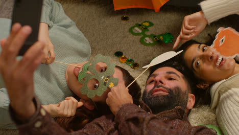Group-Of-Friends-Dressing-Up-At-Home-Lying-On-Floor-Celebrating-At-St-Patrick's-Day-Party-Posing-For-Selfie-On-Phone-1